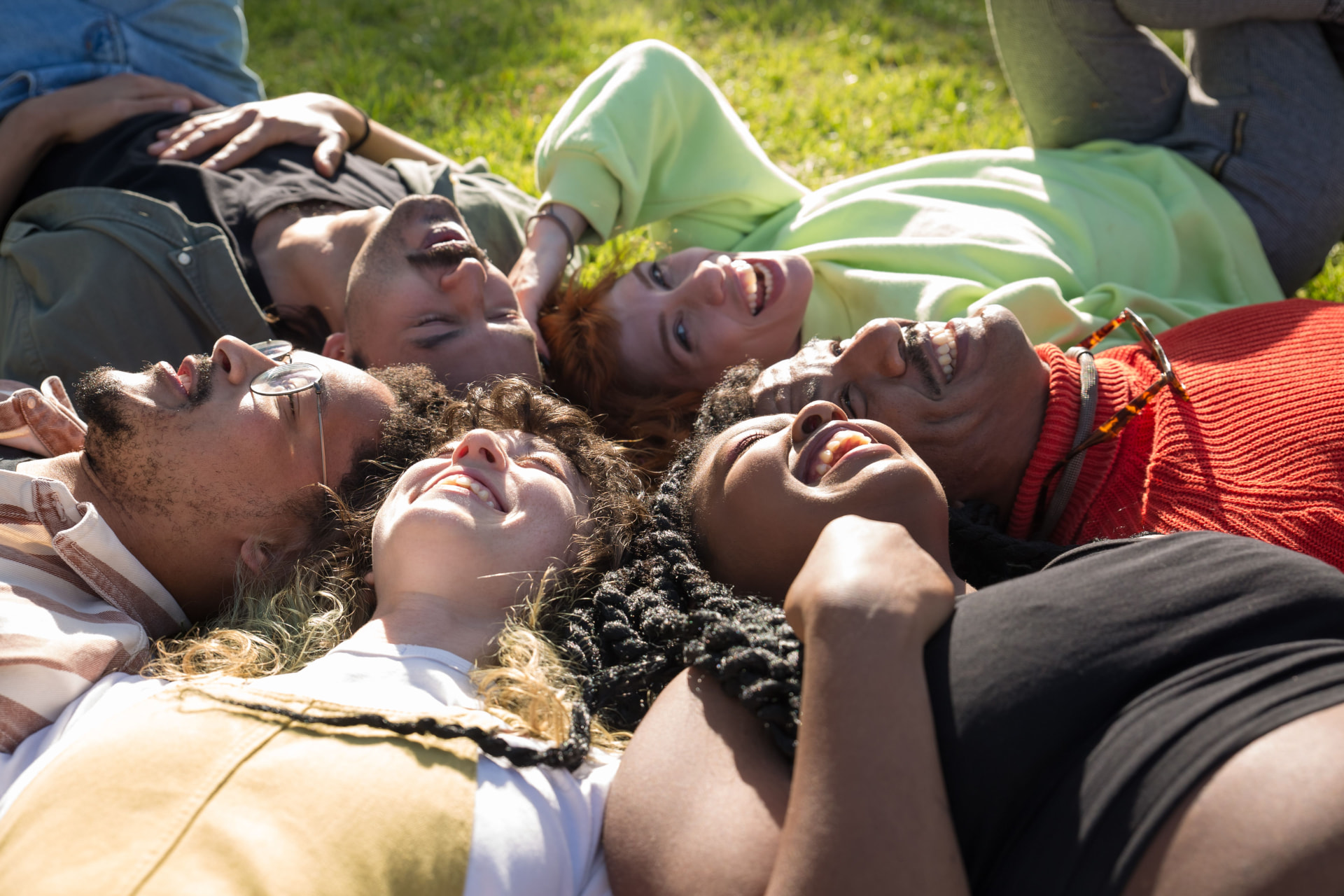 Young people lying in a circle on grass, laughing